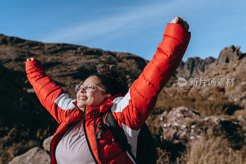 一个张开双臂的女人在Itatiaia的Pico das Agulhas Negras的踪迹上